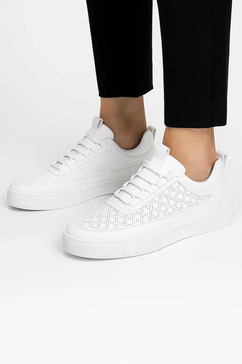 Hvide sneakers med hulmønster og polstret ankelkant, forside med snørebånd.