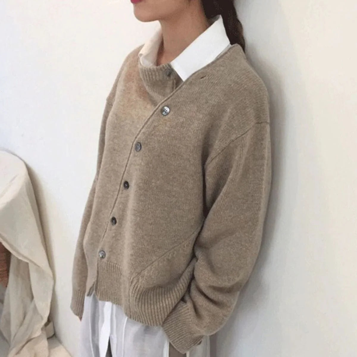Brunmeleret cardigan med asymmetrisk knaplukning og ribkanter, lange ærmer.