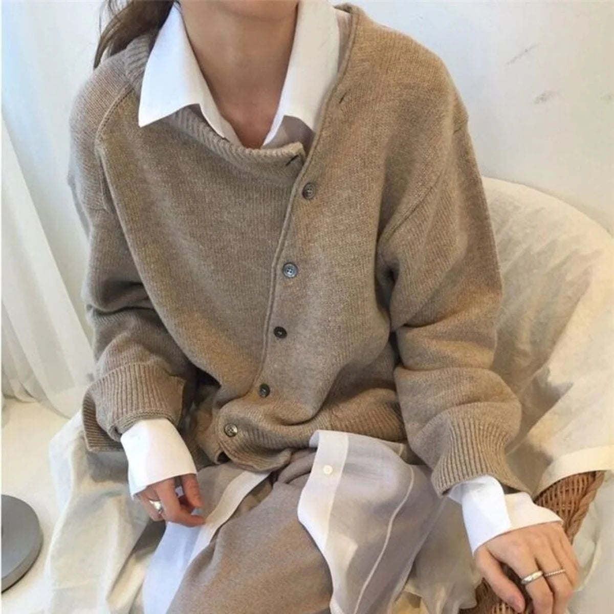 Sandfarvet cardigan med asymmetrisk knaplukning, ribkanter og lange ærmer.