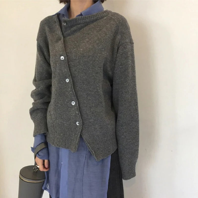Mørkegrå cardigan med knapper foran i asymmetrisk lukning og ribkanter.