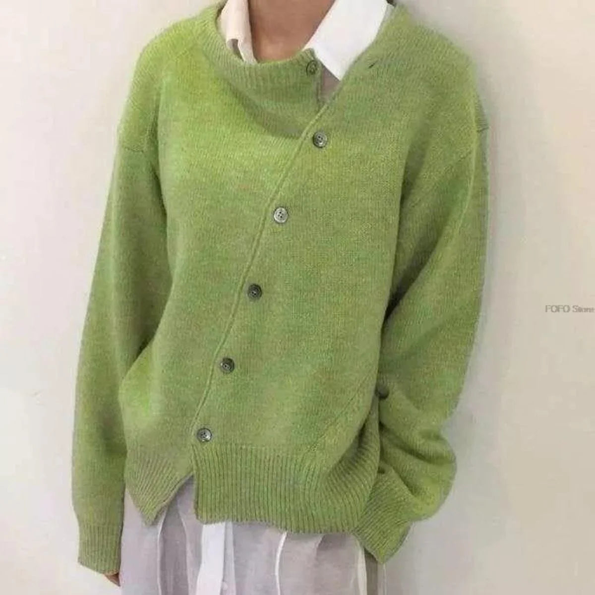 Grøn cardigan med asymmetrisk knaplukning, ribkanter og lange ærmer.