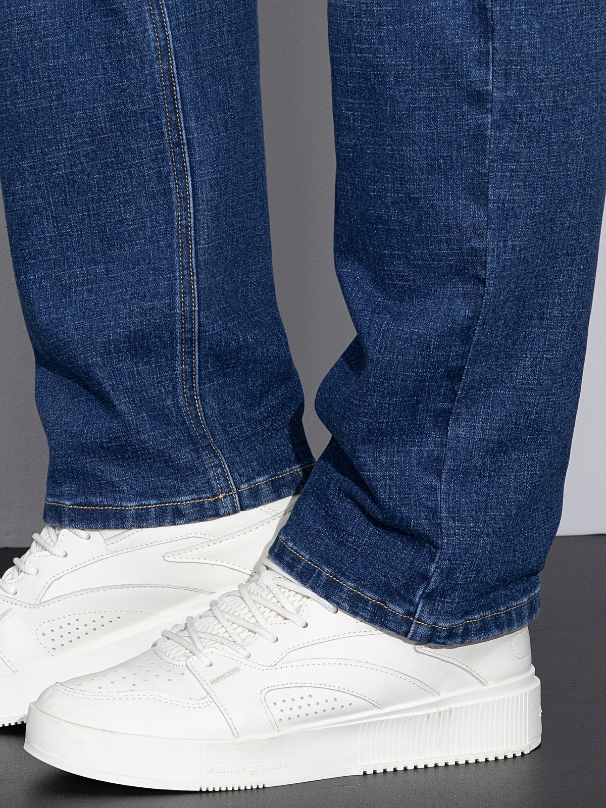 Blå jeans med lige ben og rå kant ved anklen, hvide sneakers synlige