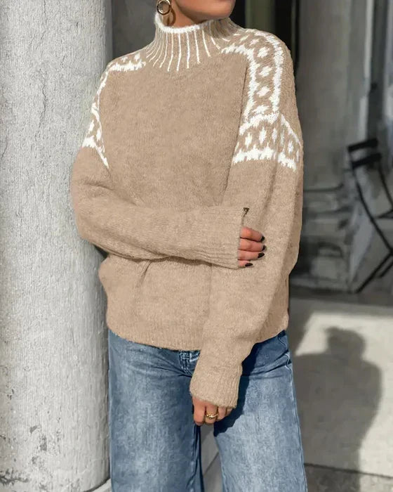 Beige strikbluse med høj hals og hvidt mønster over skulder