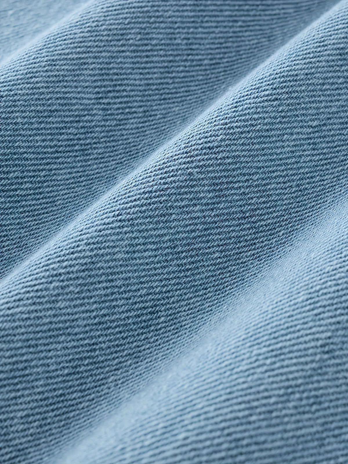 Nærbillede af lyseblåt denimstof med fin tekstur