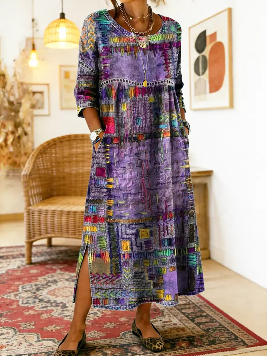 Flerfarvet maxikjole med patchwork-print og rund hals, let åben ved siden.