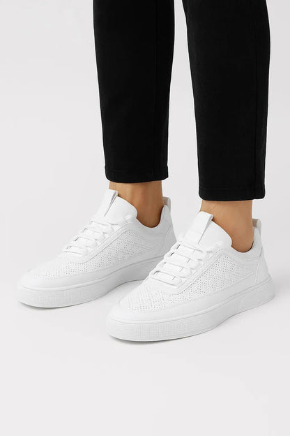 Hvide sneakers med hulmønster og polstret ankelkant, set fra siden.