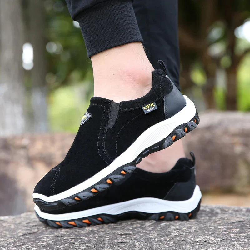 Sorte sneakers set fra siden, elastik ved skaftet og kraftig tandsål
