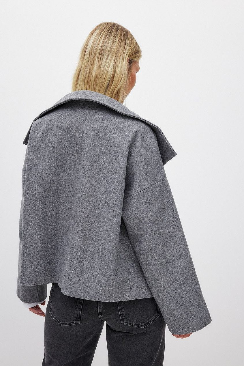 Kort boxy jakke i grå set bagfra med stor revers og dobbeltradede knapper