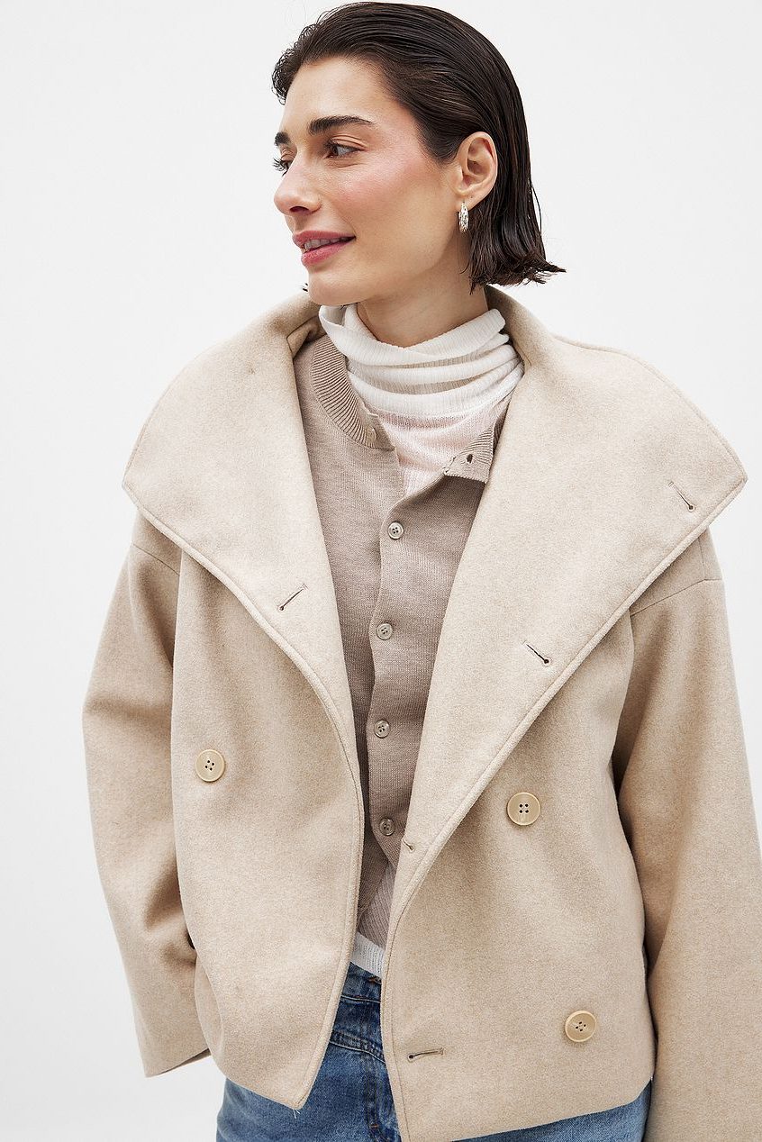 Kort boxy jakke i beige med stor revers, knaplukning foran og klaplommer